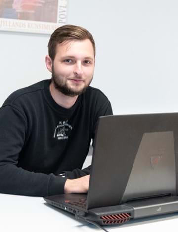 Ung mand, der sidder med computer